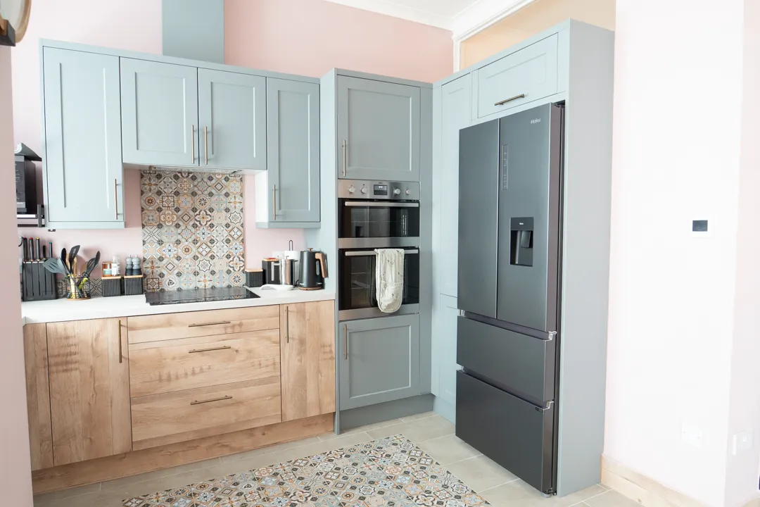 A kitchen with blue cabinets and a gray refrigerator.